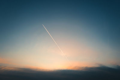 Low angle view of vapor trails in sky during sunset