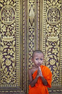 Portrait of boy in traditional clothing gesturing while standing against wall