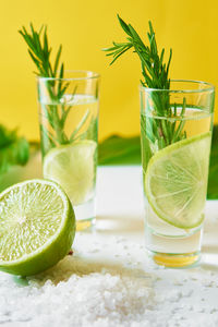 Drink with lime and rosemary on yellow background