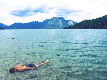 Teenager boy show how drowned body floats in low water. alpine lake, herzogstand peak, upper bavaria