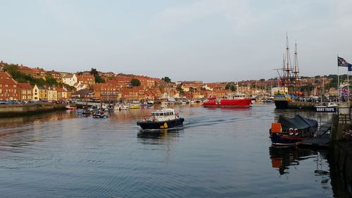 Boats moored at harbor against buildings in town