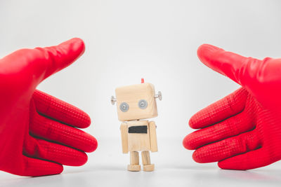 Close-up of hand holding toy over white background