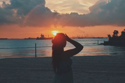 Silhouette man using mobile phone at beach against sky during sunset