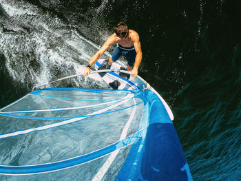 Wide-angle shot of adult man windsurfing on lake wallersee, austria