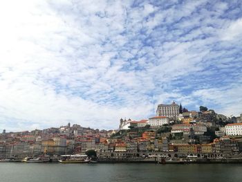 Sea by buildings against sky in city