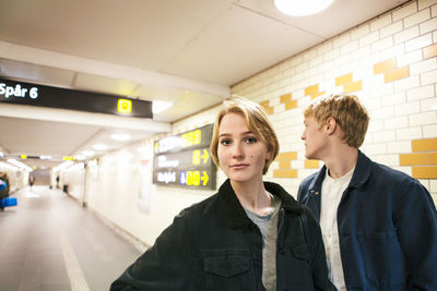 Portrait of teenage girl walking with young man in underground walkway