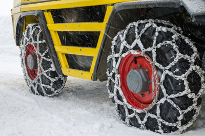 Close-up of snow chains tied on tires during snowfall