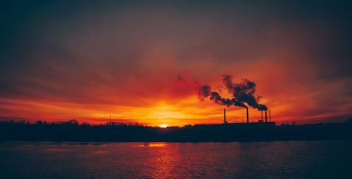 Smoke emitting from factory against sky during sunset