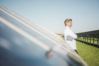 Businessman with wireless earphone using tablet at solar park