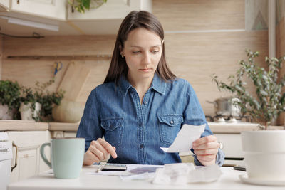 Portrait of young woman using mobile phone while sitting on table