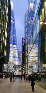 People walking on modern buildings against sky in city