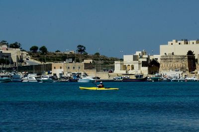 Boats in sea against clear blue sky