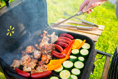 Close-up of person preparing food on barbecue grill