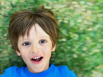 High angle portrait of cute boy lying on grassy field