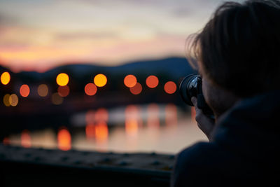 Close-up of man photographing against sky during sunset