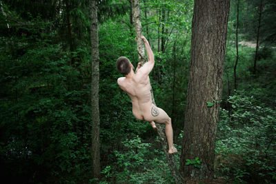 Full length of shirtless man in forest