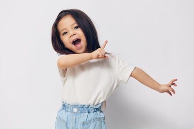 Portrait of cute girl gesturing while standing against white background