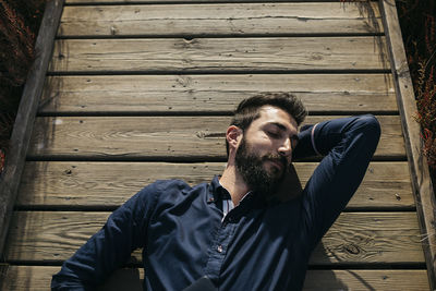 High angle view of mid adult man lying on boardwalk during sunset