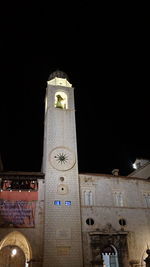 Low angle view of clock tower against sky at night