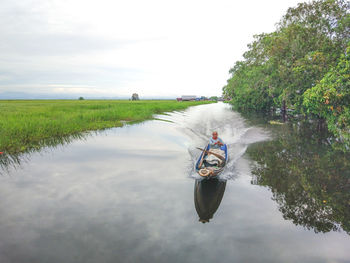 Man on boat in river against sky