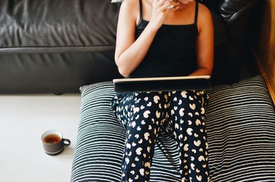 Midsection of woman with laptop sitting at home