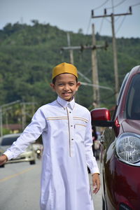 Portrait of smiling boy standing by car