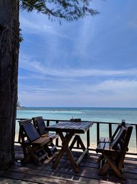 Chairs and table by sea against sky