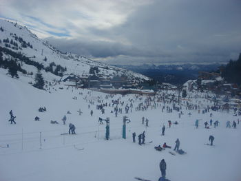 People on snow covered landscape against sky