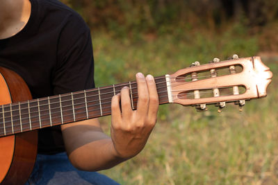Midsection of man playing guitar