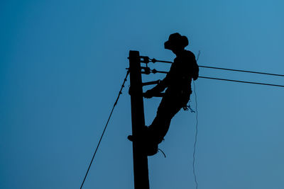 Low angle view of silhouette man against clear blue sky