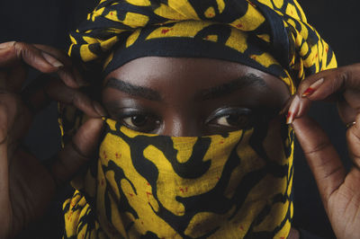 Close-up of woman wearing scarf against black background