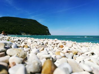 Surface level of pebble beach against blue sky