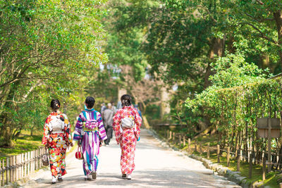 Rear view of people walking along plants