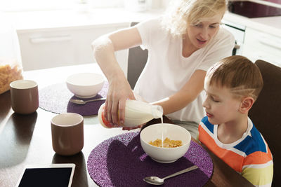 High angle view of siblings sitting on table at home