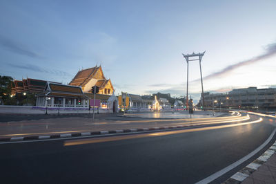 Road by buildings against sky in city