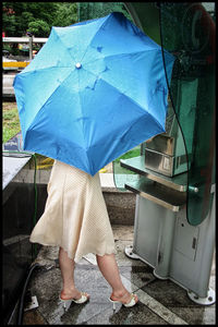 Low section of woman with umbrella standing in rain