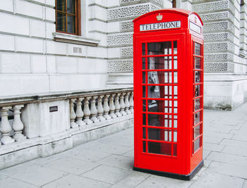 Red telephone booth on sidewalk