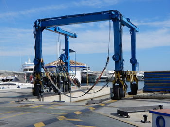 Pier and crane for vessels at fuengirola harbor in malaga province against sky.