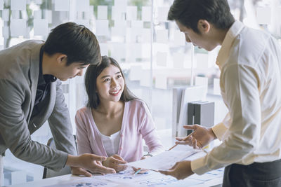 Colleagues discussing over documents at office