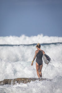 Rear view of woman on sea shore against sky