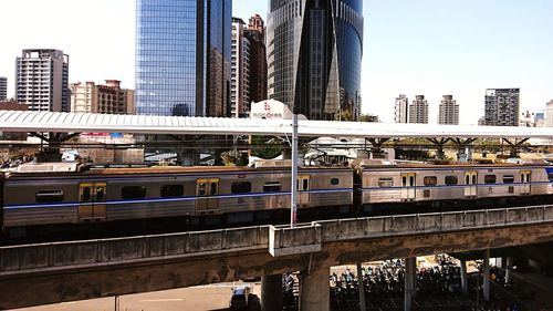 Train on bridge against buildings in city