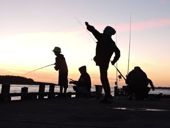 Silhouette people fishing at calm sea