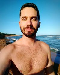 Portrait of smiling man on beach against clear blue sky