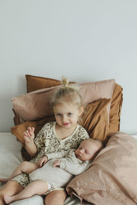 Girl with newborn sibling on bed