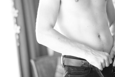 Midsection of shirtless man removing jeans