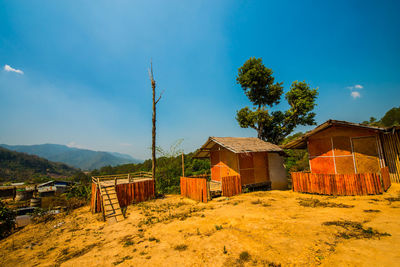 Houses by trees and mountains against blue sky