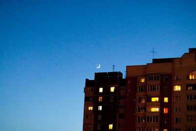 Low angle view of illuminated buildings against blue sky