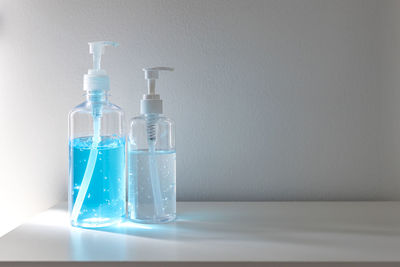 Close-up of glass bottle on table against wall