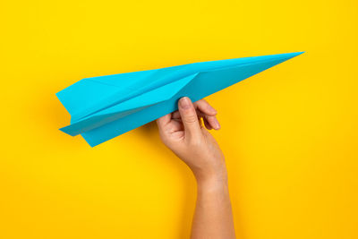 Low section of person holding paper against yellow background