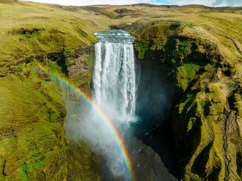 Famous skogafoss waterfall with a rainbow. dramatic scenery of iceland during sunset.